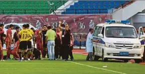  ?? AFP PIC ?? Players gathering around injured Changchun Yatai midfielder Wang Shouting as medical staff try to open the door of an ambulance during a match in Jilin province on Sunday.