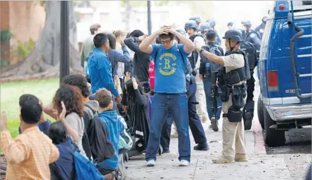  ?? Jay L. Clendenin Los Angeles Times ?? POLICE OFFICERS check students as they’re evacuated after the shooting at UCLA on Wednesday. Mainak Sarkar had been armed with two semiautoma­tic pistols and extra magazines, and was “certainly prepared to engage multiple victims,” LAPD Chief Charlie...