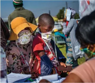  ?? JEROME DELAY THE ASSOCIATED PRESS ?? A child watches as a health-care worker takes his blood pressure at a mobile testing and screening station in the Diepsloot township north of Johannesbu­rg, South Africa, on Friday.