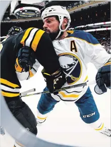  ?? MADDIE MEYER GETTY IMAGES ?? Zach Bogosian, right, of the Buffalo Sabres checks Danton Heinen of the Bruins into the boards at TD Garden in Boston on Sunday.Jack Eichel and Jeff Skinner extended their points streaks to six games.