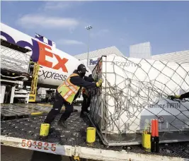  ?? COLE BURSTON The Canadian Press via AP ?? Workers unload a shipment of the Moderna COVID-19 vaccine at the FedEx hub in Toronto on April 28, 2021.