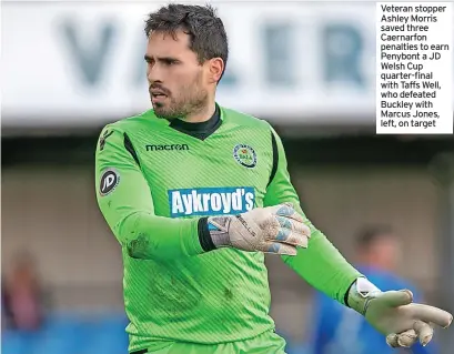  ?? ?? Veteran stopper Ashley Morris saved three Caernarfon penalties to earn Penybont a JD Welsh Cup quarter-final with Taffs Well, who defeated Buckley with Marcus Jones, left, on target