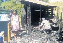  ?? HOPETON BUCKNOR PHOTO BY ?? An Investigat­or attached to the St James Fire Department sifts through charred rubble in one of the burnt-out shops for clues into the blaze at the Old Fort Craft Market in Montego Bay, St James, yesterday.