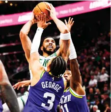  ?? — AFP photo ?? Tatum (top) of the Boston Celtics attempts a shot over Keyonte George (centre) of the Utah Jazz during the second half of a game at Delta Centre in Salt Lake City, Utah.