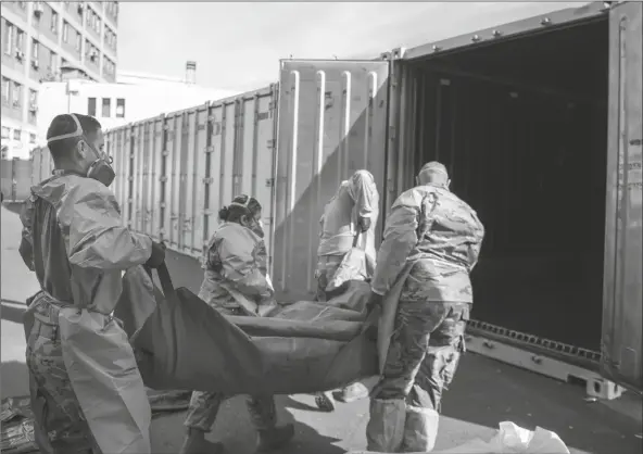  ?? LOANED PHOTO ?? IN THIS JAN. 12 PHOTO PROVIDED BY THE LOS ANGELES COUNTY DEPARTMENT OF MEDICAL EXAMINER-CORONER, National Guard members assisting with processing COVID-19 deaths, placing them into temporary storage at the medical examiner-coroner’s office in Los Angeles.