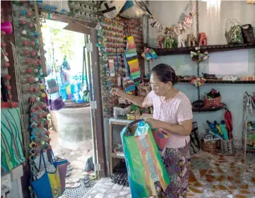  ??  ?? Local woman Wendy Neampui arranges craft made out of recycled plastics at her Chu Chu recycling shop in Dala.