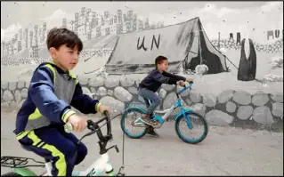  ??  ?? طفلان يمران بجدارية تحمل اسم الأمم المتحدة في مخيم الفوار شمال الخليل