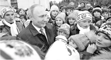  ??  ?? Putin (second left) speaks with children in Cathedral Square (Sobornaya Square) at the Kremlin before a meeting with members of the government in Moscow, Russia. — Reuters photo