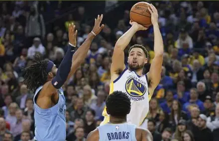 ??  ?? Golden State Warriors guard Klay Thompson (in white) attempts to shoot against Memphis Grizzlies’ guards during the fourth quarter at the Oracle Arena on Monday. REUTERS PIC
