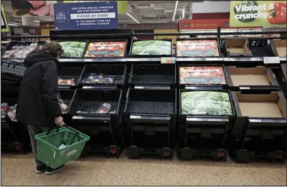  ?? YUI MOK — PA VIA AP ?? A customer checks almost empty fruit and vegetable shelves at an Asda in east London on Tuesday. Several British supermarke­t chains have limited the amount of some fresh produce customers can buy amid shortages blamed on bad weather in Spain and Morocco.