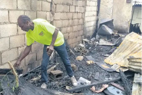  ?? PHOTO BY PAUL CLARKE ?? Donovan Richards sifts through the charred reamins of his home yesterday.