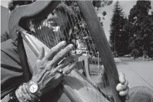  ?? Michael Macor / The Chronicle ?? Matthew Malie plays a wooden harp at Berkeley’s Martin Luther King Jr. Civic Center Park. Malie said he sleeps in a stairwell at UC Berkeley.