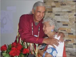  ??  ?? Joseph Naytowhow, who did honour songs at the book launch, gives a hug to Métis elder Cecile Blanke after he made a gift presentati­on to her.