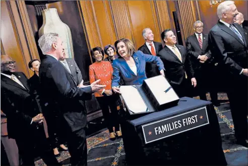  ?? WIN MCNAMEE/GETTY ?? House Speaker Nancy Pelosi, flanked by a bipartisan group of House members, shows off the stimulus bill known as the CARES Act after the bill was passed Friday.