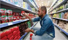  ?? (Reuters) ?? A SHOP WORKER arranges cans of Iranian tomato paste this week at a supermarke­t in Najaf, Iraq.