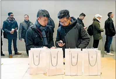  ?? AP/CHARLES REX ARBOGAST ?? Two visitors from China configure an iPhone X they bought at an Apple store in Chicago. The U.S. Commerce Department released retail sales data for October on Wednesday.