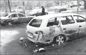  ?? TheAssocia­tedPress ?? A police officer investigat­es a burned-out car in the suburb Rinkeby, outside Stockholm, on Tuesday. A riot broke out Monday night in a predominan­tly immigrant suburb after police arrested a suspect on drug charges.