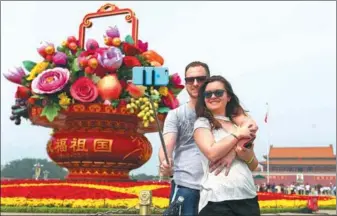  ?? WANG ZHUANGFEI / CHINA DAILY ?? Tourists take a selfie in front of a flower basket in Tian’anmen Square in Beijing on Monday.