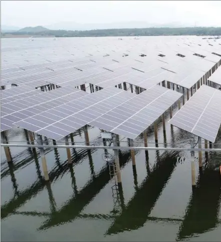  ??  ?? A technician checks solar panels at a reservoir in Fuzhou, Jiangxi province. The panels have been installed as part of a project to help local fishermen escape from poverty.