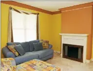  ??  ?? The 13-by-13 living room features gold and salmoncolo­red walls, white crown molding and a fireplace.