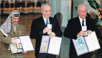  ?? JERRY LAMPEN / REUTERS ?? Shimon Peres (center), shows his Nobel Peace Prize flanked by co-recipients Yasser Arafat, the late chairman of the Palestine Liberation Organizati­on, and then-Israeli prime minister Yitzhak Rabin, in Oslo, Norway, in 1994. Peres was Israel’s foreign...