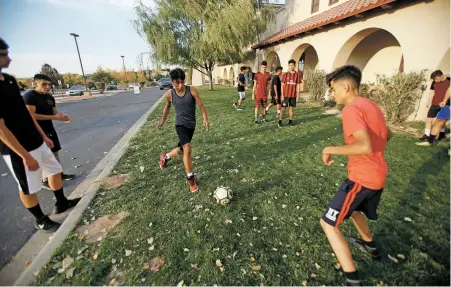  ?? PHOTOS BY LUIS SÁNCHEZ SATURNO/THE NEW MEXICAN ?? TOP: Kurtis Montoya, left, head coach of Tierra Encantada, watches as senior Mario Juarez practices Thursday with the team on a 15 foot wide patch of grass in front of their new building. ABOVE: Freshmen Joey Vazquez, left, and Omar Orozco run drills...