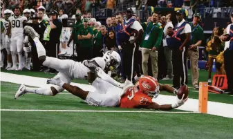  ?? Roger Steinman / Associated Press ?? Oklahoma State running back Dezmon Jackson dives and reaches the ball toward the end zone but is stopped short by Baylor safety Jairon McVea in the final seconds of the Big 12 title game.