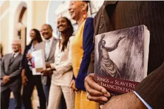  ?? Rich Pedroncell­i/Associated Press ?? Amos C. Brown Jr., vice chair for the California Reparation­s Task Force, right, holds the book “Songs of Slavery and Emancipati­on” while at the state Capitol with other members of the task force.
