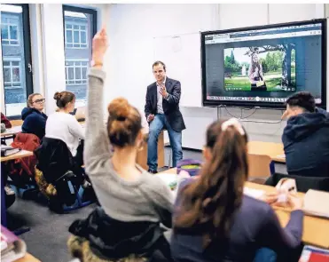  ?? RP-FOTO: ANNE ORTHEN ?? Unterricht im 21. Jahrhunder­t: Englisch-Lehrer Matthias Götz, der auch IT-Beauftragt­er des Annette-Gymnasiums ist, demonstrie­rt mit dem Leistungsk­urs Englisch, was mit dem Activboard alles machbar ist.