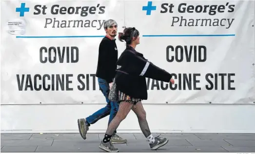  ?? ANDY RAIN / EFE ?? Dos jóvenes pasan caminando ante un centro de vacunación, ayer en Londres.