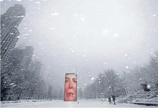  ?? Photo: REUTERS ?? Whiteout: Two men walk near Chicago’s Crown Fountain, an interactiv­e video display which shows faces of the city’s residents. Several of the city’s top tourist attraction­s closed early because of the weather.