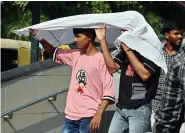  ?? ?? People cover their heads with a cloth to protect themselves from the sun on a hot summer day, in New Delhi on Saturday.