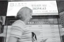  ?? ASSOCIATED PRESS ?? A woman walks past a bank electronic board showing the Hong Kong share index at Hong Kong Stock Exchange. Asian shares were moderately lower on Wednesday after U.S. stocks succumbed to a sell-off in the final minutes of trading, snapping a three-day...