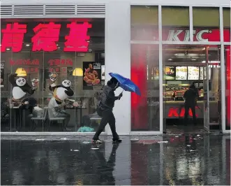  ?? ANDY WONG/THE ASSOCIATED PRESS ?? A woman walks past a KFC restaurant in Beijing Wednesday. Chinese state newspapers have criticized protests by nationalis­ts against KFC restaurant­s and other U.S. targets.