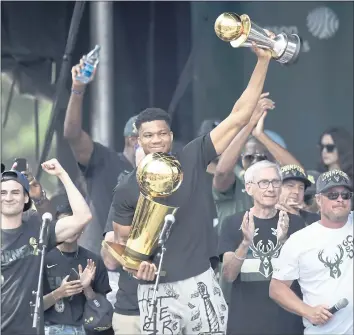  ?? PATRICK MCDERMOTT – GETTY IMAGES ?? Giannis Antetokoun­mpo celebrates with the Larry O’Brien and Finals MVP trophies during the Milwaukee Bucks’ 2021 NBA championsh­ip victory parade on July 22. The Bucks begin their title defense tonight against the Brooklyn Nets.