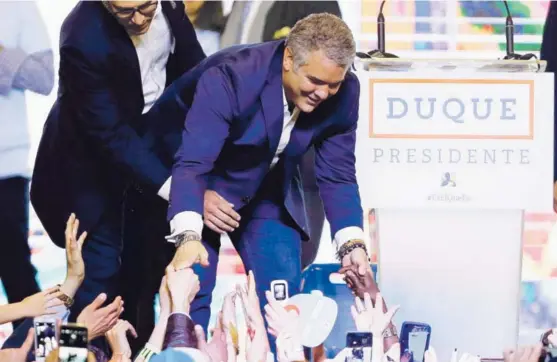  ?? AP Y AFP ?? Iván Duque, presidente electo de Colombia, saludaba a sus seguidores, anoche, en Bogotá, una vez confirmada su victoria en las elecciones. El exmandatar­io Álvaro Uribe (centro, abajo) celebró el triunfo del exsenador en su casa en Rionegro,...