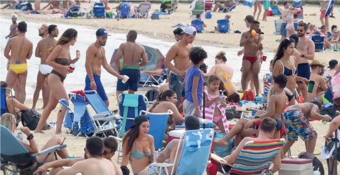  ?? JiM MicHAuD pHOTOS / BOSTOn HERAlD ?? GETTING SOME SUN: Packed Beaches, like here the M Street Beach, as temperatur­es soared into the 90s again Sunday in South Boston. Inset below, boats and personal water craft fly around Boston Harbor as temperatur­es soared into the 90s.