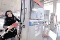  ?? — Reuters ?? An Iranian woman puts a nozzle back after refuelling her car at a gas station in Tehran.