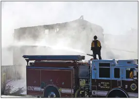  ?? AP/MARCIO JOSE SANCHEZ ?? A firefighte­r pours water on a house Friday in Santa Clarita, Calif., where a wildfire that forced the evacuation of 50,000 people has spread through canyons north of Los Angeles. Strong winds are driving that fire and another in Northern California.