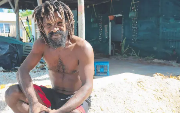  ??  ?? HARD WORK: Yam Island resident Richard Billy sits on the sand wall he built around a friend's home as a king tide flooded low-lying homes.