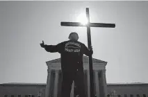  ?? [AP PHOTO/PATRICK SEMANSKY] ?? Tom Alexander holds a cross as he prays prior to rulings outside the Supreme Court on Wednesday on Capitol Hill in Washington, D.C.