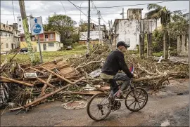  ?? VICTOR J. BLUE / NEW YORK TIMES ?? Juan Perez rides last month through a neighborho­od in Arecibo, Puerto Rico, that was flooded by Hurricane Maria. The storm lashed the Caribbean island and U.S. territory with Category 4 winds, leaving millions without power.