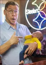  ?? Jessie Wardarski/Post-Gazette ?? Curt Wootton of Pleasant Hills gets in character as “Pittsburgh Dad,” as he holds his daughter, Penny, 2 months.