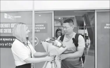  ?? XINHUA ?? The first Chinese traveler to arrive at Minsk National Airport in Belarus under the new visa-free agreement receives flowers from an airport employee. China and Belarus implemente­d visa-free policies for their respective citizens on Aug 10.