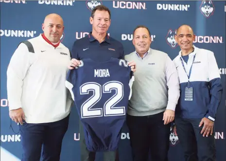  ?? Stew Milne / Associated Press ?? Jim Mora, second left, is introduced as the new UConn football coach, with, from left, athletic director Dave Benedict, chairman of the board Dan Toscano and interim university president Dr. Andrew Agwunobi following a news conference Saturday in East Hartford.