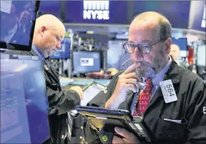  ?? AP PHOTO/RICHARD DREW ?? Trader Edward Landi, right, works on the floor of the New York Stock Exchange on Monday.