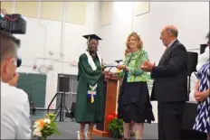  ?? PETER CURRIER — LOWELL SUN ?? Khadija Turay receives the very first diploma in the history of the Collegiate Charter School of Lowell from founding member and Board of Trustees Vice President Kathleen Mccarthy during the school’s first ever commenceme­nt ceremony on June 1, 2023 as founding member and Board of Trustees President Walter Mcgrail looks on.