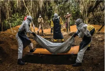  ?? DANIEL BEREHULAK/THE NEW YORK TIMES ?? A burial team in Liberia in 2014 inters one of the 11,300 people killed during the West African Ebola crisis.