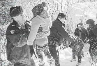  ?? PAUL CHIASSON THE CANADIAN PRESS FILE PHOTO ?? RCMP officers help migrants enter Quebec from the U.S. last year.