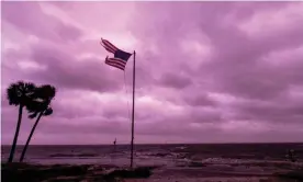  ?? Photograph: Mark Wallheiser/Getty Images ?? An American flag battered by Hurricane Michael continues to fly in the in the purple colored light of sunset at Shell Point Beach on October 10, 2018 in Crawfordvi­lle, Florida.